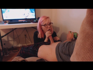bespectacled girl with pink hair gives a blowjob to a guy while he plays computer - 